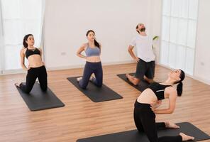 A yoga teacher and her group of students do basic yoga poses in a classroom in a fitness center in the studio. photo