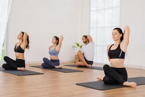 A yoga teacher and her group of students do basic yoga poses in a classroom in a fitness center in the studio. photo