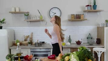 feliz vegano menina com fino cintura dançando, cantando dentro cozinha. cru vegetal nutrição dieta conceito video