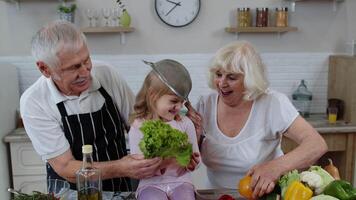 senior vrouw en Mens met kleinkind meisje maken een grappig dans met zeef en groenten Bij huis video