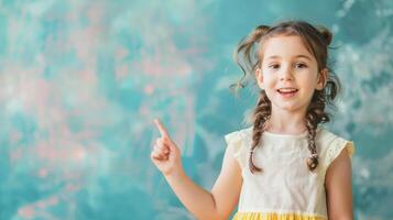 little happy child points with his index finger at something on a light blue wall, space for text photo