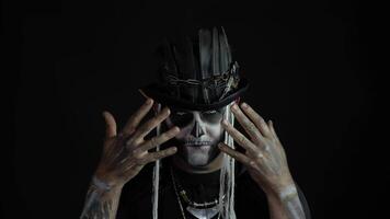 Scary guy in carnival costume of Halloween skeleton against black background. Man skull makeup video