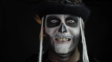 Siniestro hombre cara en esqueleto Víspera de Todos los Santos cosplay apareciendo en negro antecedentes. haciendo caras, sonriente video