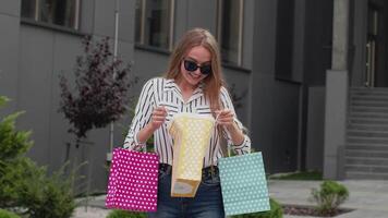 adolescente niña en de moda ropa con multicolor compras bolsas. negro viernes rebaja descuentos concepto video