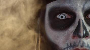 Close-up macro shot of creepy, scary man face with skeleton makeup opening eyes with white pupil video