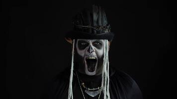 Frightening man in skeleton Halloween cosplay costume. Guy in creepy skull makeup making faces video