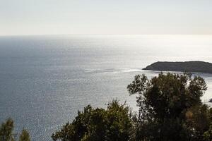 The sea surface of the Adriatic Sea. An island with green trees. View from above. Montenegro. Budva. Horizontal. photo