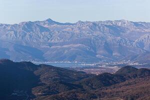 pintoresco panorámico ver de el ciudad, mar y montaña rango debajo azul cielo a través de verde colinas en verano. antecedentes. para texto. bandera. tarjeta postal. horizontal foto