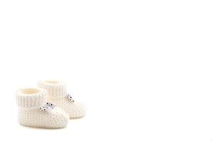 White crochet baby booties with black polka dot bows isolated on a white background. Handmade baby booties. Photo in high quality