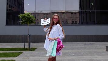 Joyful teen girl showing Black Friday inscription, smiling, looking satisfied with low prices video