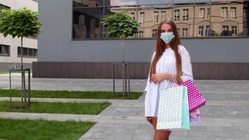 adolescente ragazza con multicolore shopping borse indossare proteggere maschera. nero Venerdì durante coronavirus video