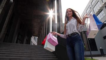 Girl walking and showing Black Friday inscription on shopping bags, rejoicing discounts in store video