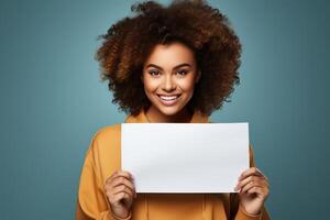 A girl with afro curls holds a blank paper with a mockup in her hands. Person with white banner isolated on studio background. photo