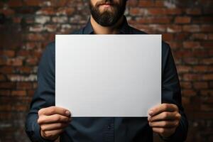 a middle-aged man holds a sheet of white paper mockup in his hands. photo