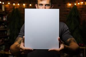 a young businessman guy holds a white sheet of paper in his hands on the background of a cafe. photo