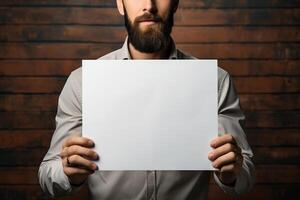 a middle-aged man holds a sheet of white paper mockup in his hands. photo