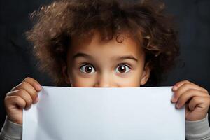 Funny child boy hiding behind blank white advertising billboard with copy space and peeking out . photo