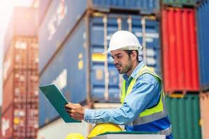 Engineer wears PPE checking container storage with cargo container background at sunset. Logistics global import or export shipping industrial concept. photo