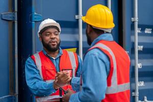 retrato de dos africano ingeniero o capataz usa ppe sacudida mano con carga envase antecedentes a puesta de sol. logística global importar o exportar Envío industrial concepto. foto