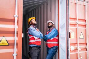 Portrait of Two African Engineer or foreman wears PPE pointing up the future  with cargo container background at sunset. Logistics global import or export shipping industrial concept. photo