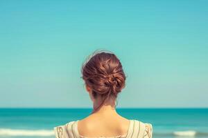 A woman looks towards the sea, rear view. Minimal pastel colors. photo