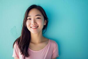 joven sonriente asiático mujer en frente de el azul pared foto