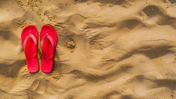 Red flip flops on beach sand, top view. Summer holiday background, copy space. photo
