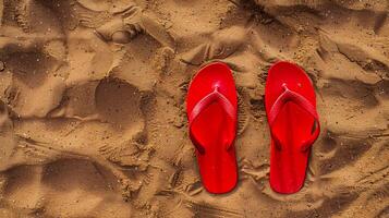 Red flip flops on beach sand, top view. Summer holiday background, copy space. photo