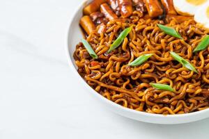 jjajang rabokki - fideos instantáneos coreanos o ramyeon con pastel de arroz coreano o tteokbokki y huevo en salsa de frijoles negros foto