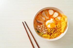 egg noodles with pork and meatball in spicy soup photo