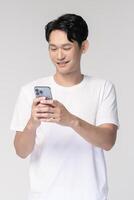 Portrait of young smiling asian man using smartphone over white background photo