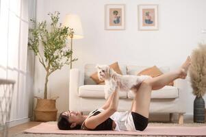 joven mujer en ropa de deporte haciendo meditación práctica y yoga con linda perro en vivo habitación, sano estilo de vida, mental salud concepto. foto