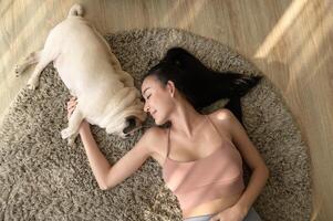 Happy young asian woman cuddling and spending time with cute dog in living room. photo