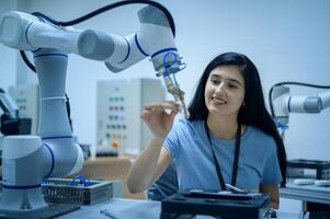 Female Robotics engineer working with Programming and Manipulating Robot Hand, Industrial Robotics Design, High Tech Facility, Modern Machine Learning. Mass Production Automatics. photo