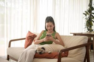 Happy young asian woman cuddling and spending time with cute dog in living room. photo