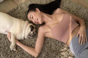 Happy young asian woman cuddling and spending time with cute dog in living room. photo