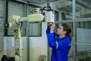 Male Robotics engineer working with Programming and Manipulating Robot Hand, Industrial Robotics Design, High Tech Facility, Modern Machine Learning. Mass Production Automatics. photo