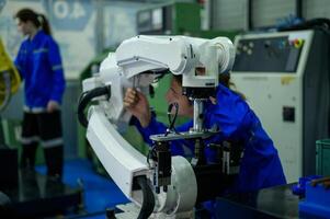 Male Robotics engineer working with Programming and Manipulating Robot Hand, Industrial Robotics Design, High Tech Facility, Modern Machine Learning. Mass Production Automatics. photo