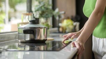 asiático mujer Cocinando y oliendo saboreo sopa en un maceta en el cocina mesa a hogar. foto