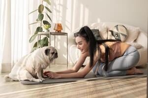 asiático mujer en ropa de deporte hacer ejercicio y haciendo yoga con linda perro en vivo habitación a hogar, sano estilo de vida, mental salud concepto. foto