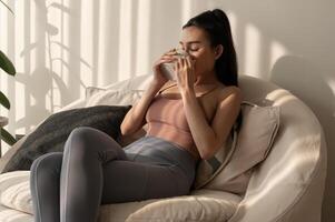 Young asian woman enjoying having coffee in living room at home photo