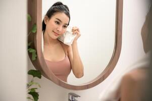 hermosa asiático mujer es Lavado y limpieza su cara foto