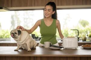 Asian woman preparing coffee and toast bread for breakfast enjoy with dog at the kitchen table in the morning photo