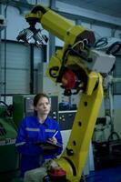 Female Robotics engineer working with Programming and Manipulating Robot Hand, Industrial Robotics Design, High Tech Facility, Modern Machine Learning. Mass Production Automatics. photo