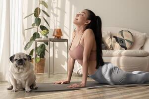 asiático mujer en ropa de deporte hacer ejercicio y haciendo yoga con linda perro en vivo habitación a hogar, sano estilo de vida, mental salud concepto. foto