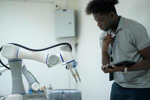 Trainee Robotics engineer learning with Programming and Manipulating Robot Hand, Industrial Robotics Design, High Tech Facility, Modern Machine Learning. Mass Production Automatics. photo