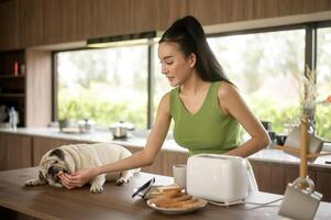 Asian woman preparing coffee and toast bread for breakfast enjoy with dog at the kitchen table in the morning photo