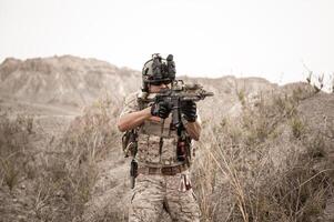 Soldiers in camouflage uniforms aiming with their riflesready to fire during military operation in the desert soldiers training  in a military operation photo