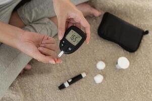 Close up of woman checking blood sugar level by using Digital Glucose meter, health care, medicine, diabetes, glycemia concept photo