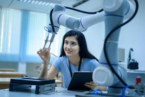 Female Robotics engineer working with Programming and Manipulating Robot Hand, Industrial Robotics Design, High Tech Facility, Modern Machine Learning. Mass Production Automatics. photo